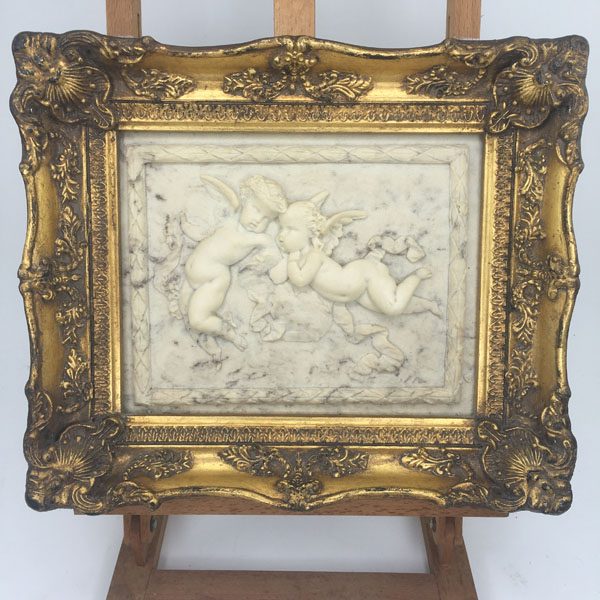 Alabaster putti plaque in ornate gesso frame